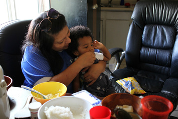 Alondra Ruiz feeds her grandson Gregory while visiting with Win La Bar's family during afternoon practice pick-up. Phoenix, Arizona, Sept. 18, 2015. (VOA/Victoria Macchi)